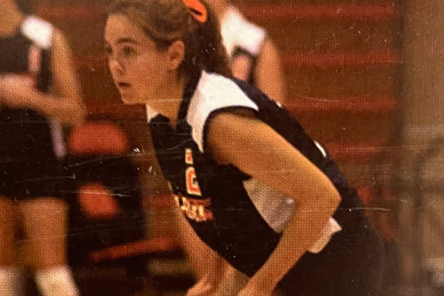 Amanda Meixel is playing volleyball on the court. She is bent in ready position, has her ISU unifrom on, and a bow in her hair.