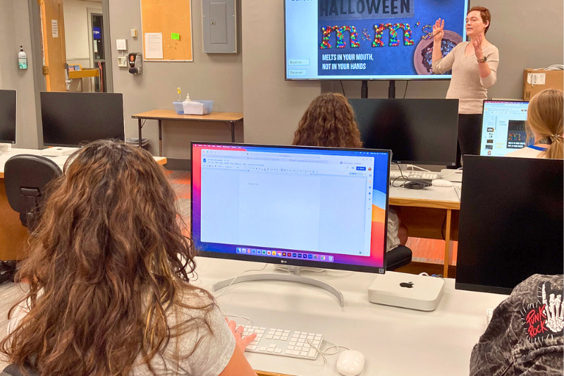 Students in class with computers while professor lectures