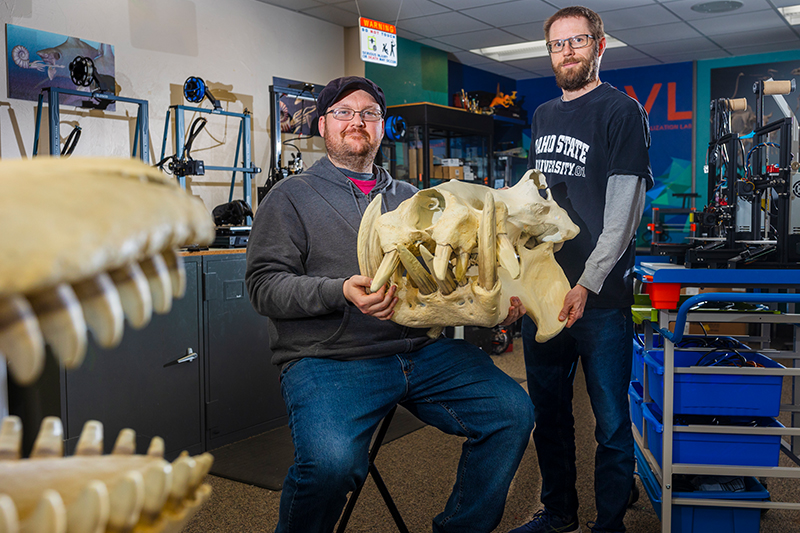 Tim Gomes, manager of the Idaho Virtualization Laboratory, and Leif Tapanila, director of the Idaho Museum of Natural History and professor of geosciences at Idaho State University, pose with a 3D-printed replica of a hippopotamus skull at the IMNH.