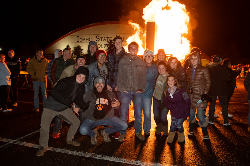 Students pose in front of the Homecoming Bonfire