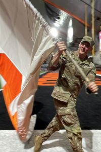 An ISU cadet in Army fatigues swings an orange and white ISU flag