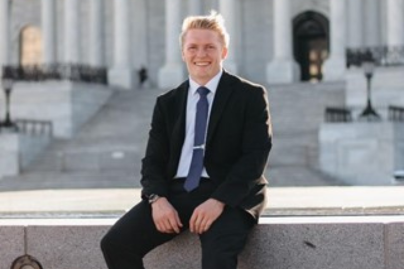 A student in a suit sitting in front of a building