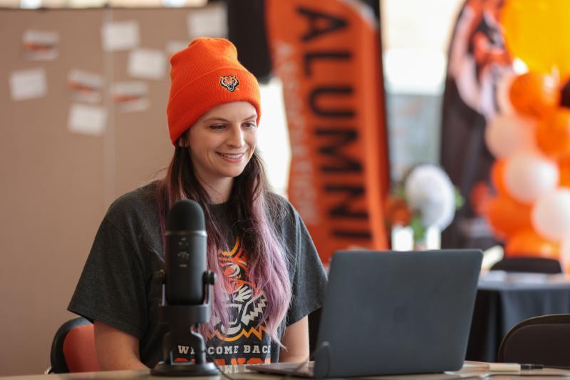 Student in ISU gear sitting in front of a computer and microphone