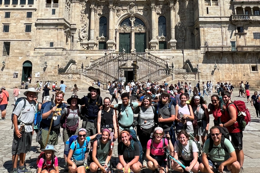 A large group of students pose for a photo outside of an ornate European building