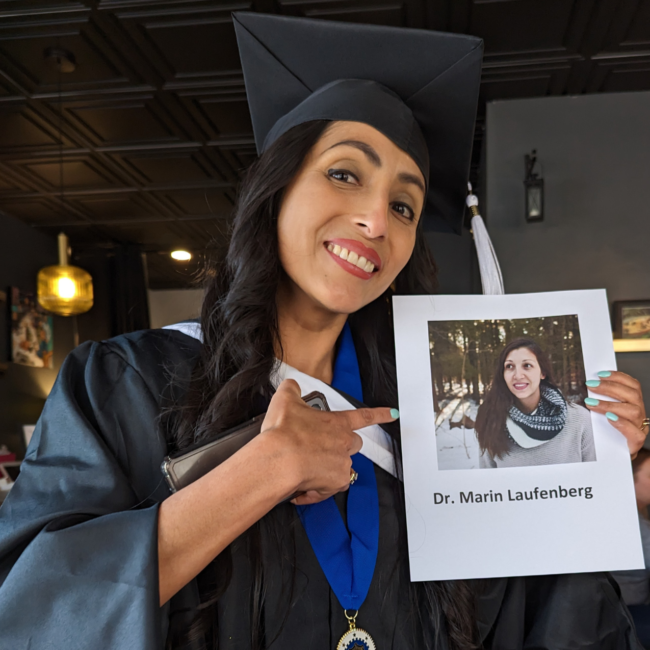 A student in cap and gown holds a program with her photo on it