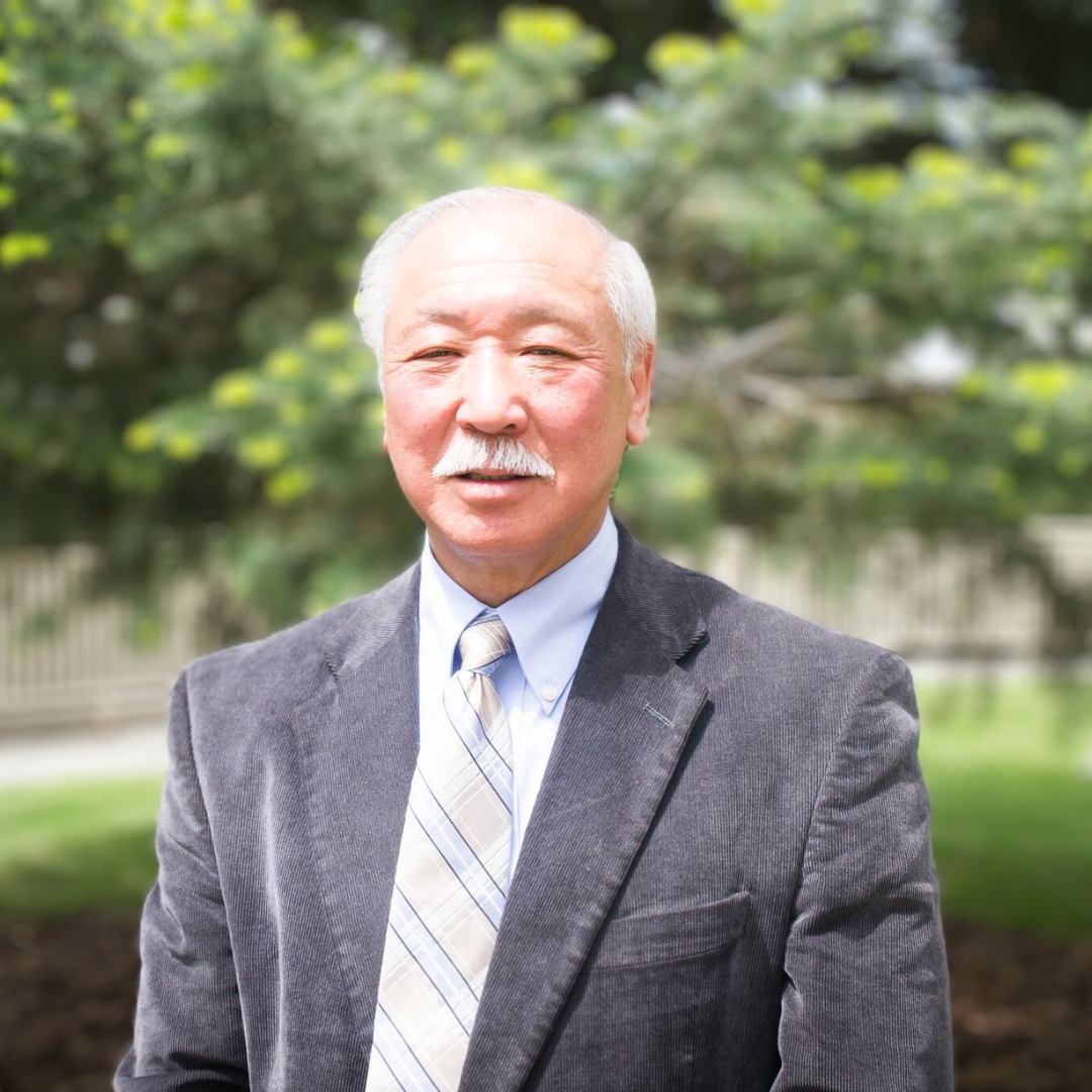 Victor Joe standing in front of green foliage outdoors