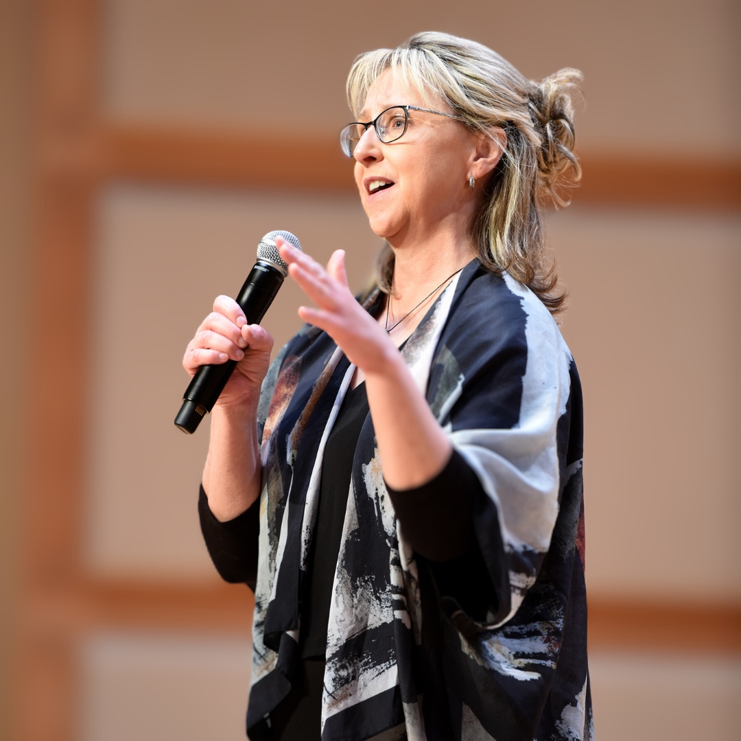 Kandi stands on stage holding a microphone