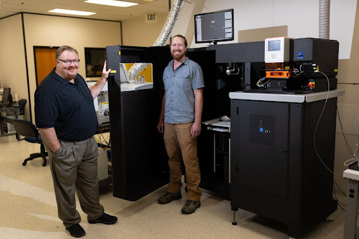 Andy Speer, left, and Christian Gattung pose for a photo beside ISU's new mass spectrometer and laser ablation system.