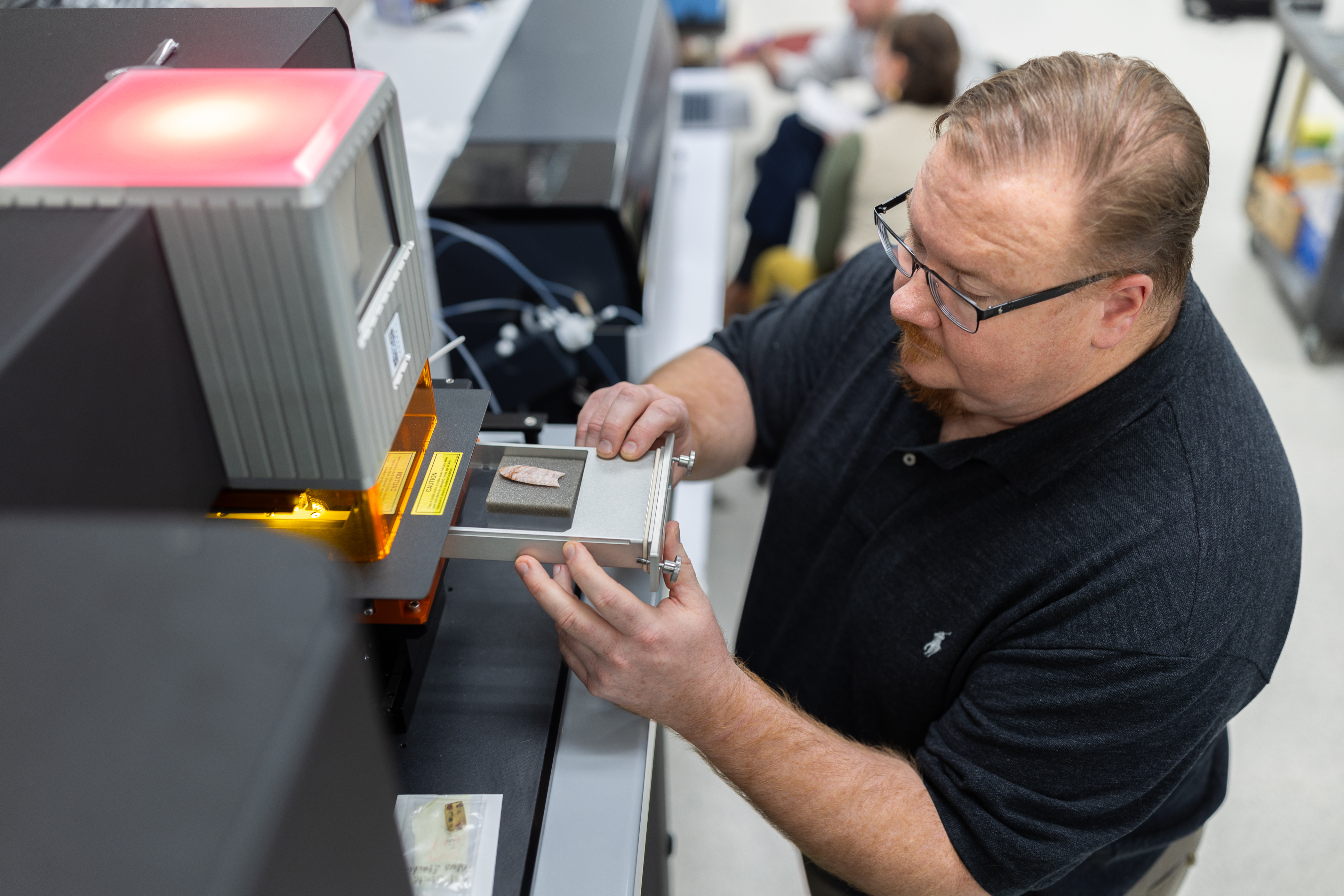 Andy Speer loads a small sample into the sample box of a machine