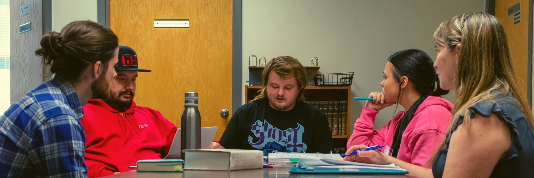 4 students sit around a table with professor Evan Rodriguez having a philosophy discussion