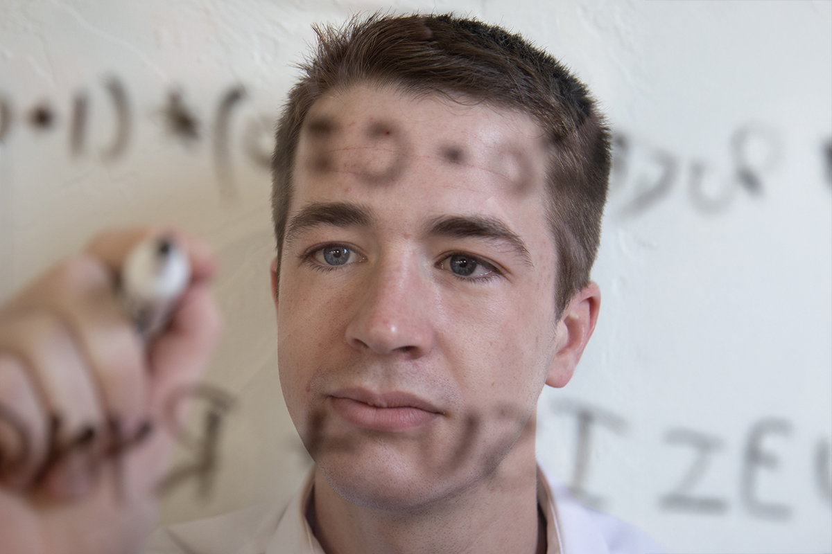 Student works on a math problem on clear board