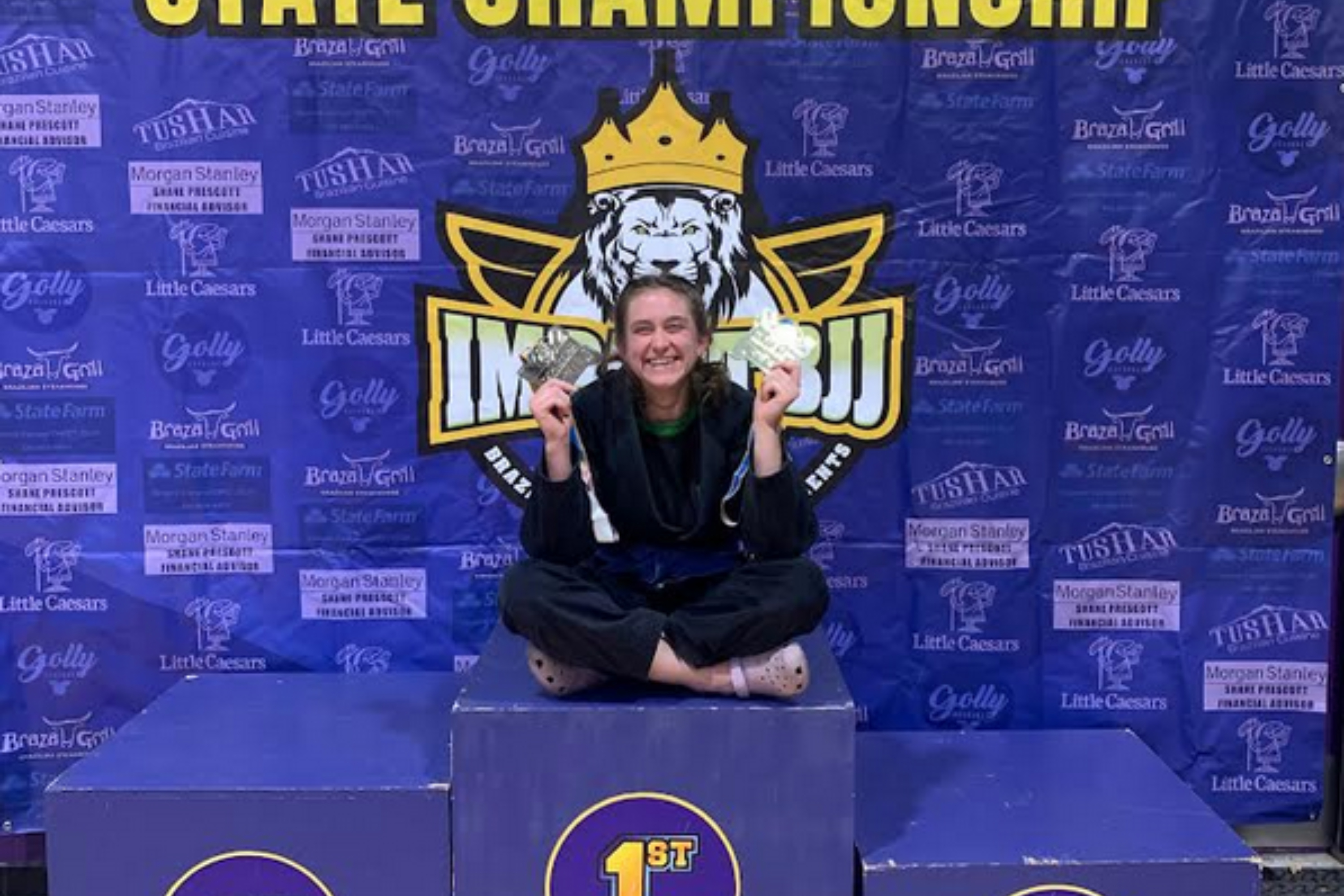 ISU Student Eliana CraigSmith poses on pedestal holding gold and silver medals