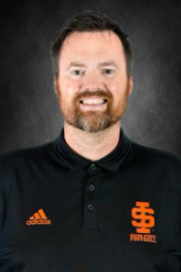 A man with light skin tone, short hair, and a reddish beard, wearing an ISU polo shirt.