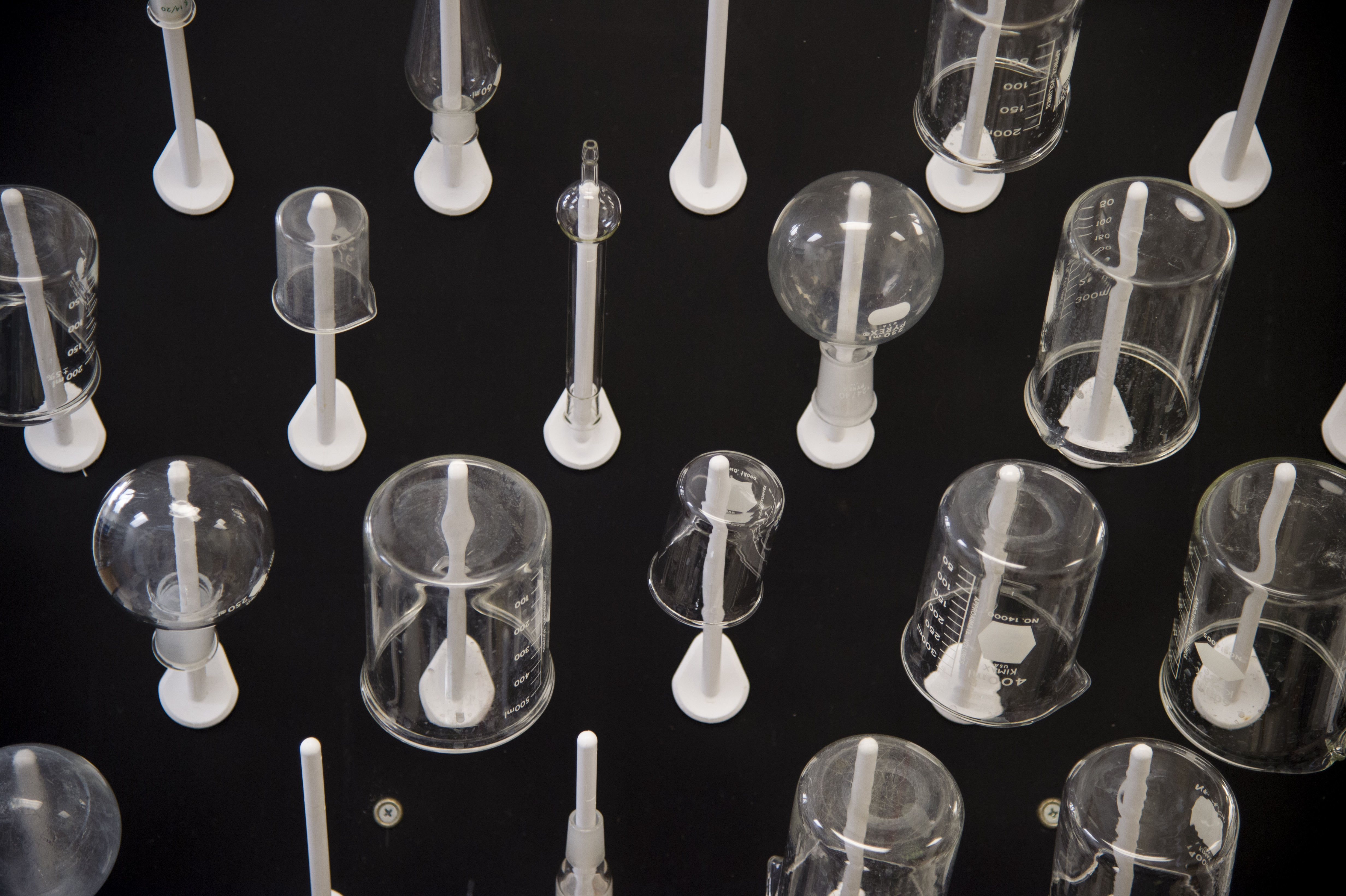 Photo of various beakers and flasks lined up on a black background to show off the various sizes and shapes.