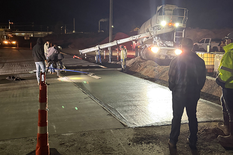 Crew members perform finishing work on the first Sweetcrete pad. This innovative concrete blend uses less cement and is cheaper to produce while still being as strong as conventional concrete developed at Idaho State University.