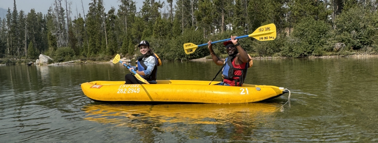 two GIS students in a kayak on a calm lake