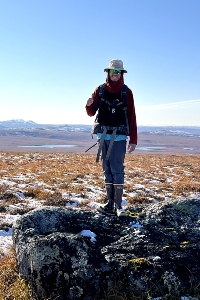 Brandon Yokeley standing on a rock outside with visible snow left over on the ground