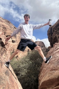 Zachary Ellia straddled between two large rock faces, holding a water bottle