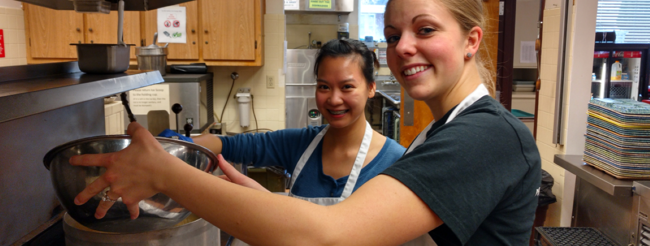 Two female students cooking at senior kitchen