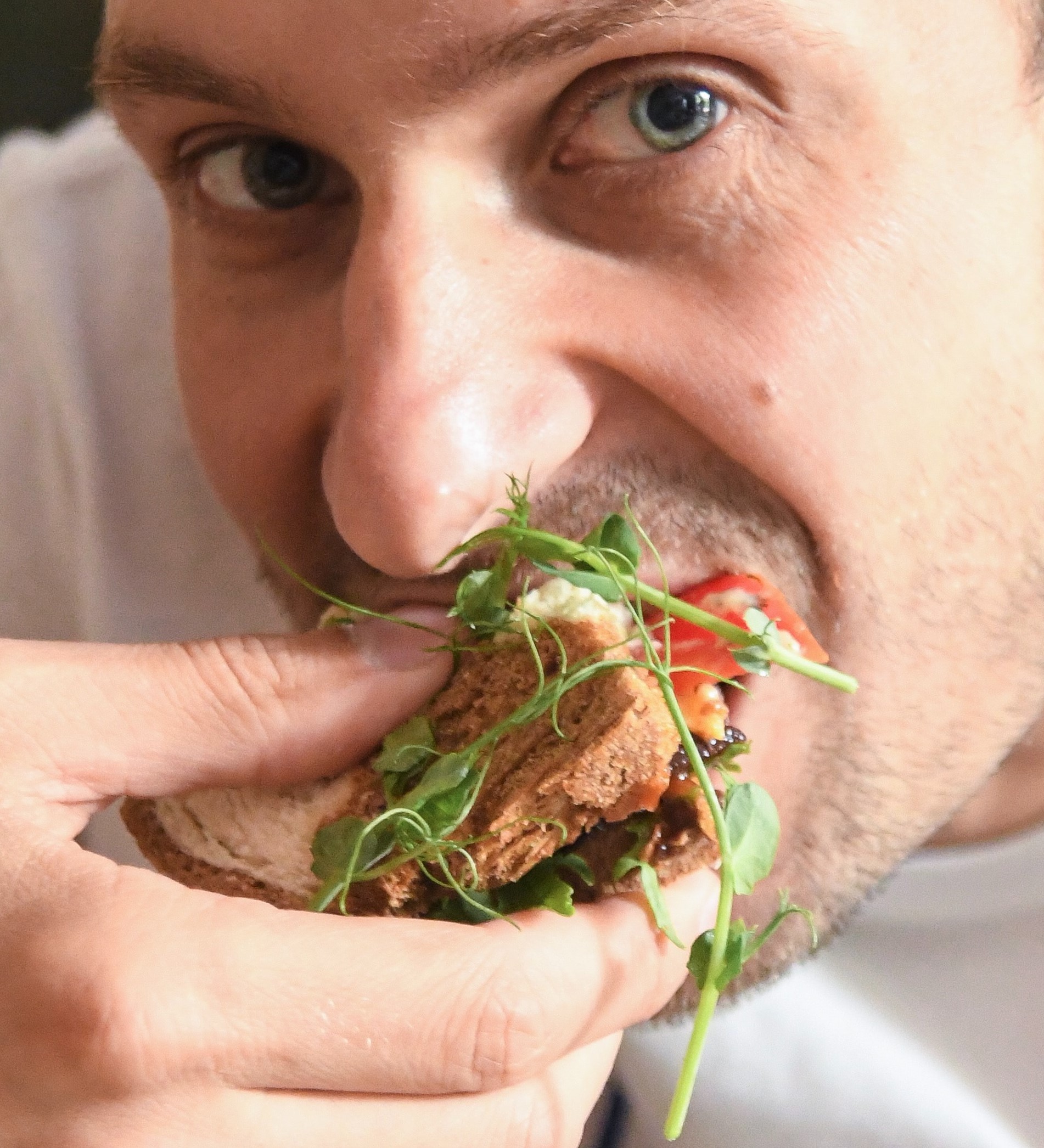 Male athlete eating sandwich, which contains carbohydrates, protein, and fat