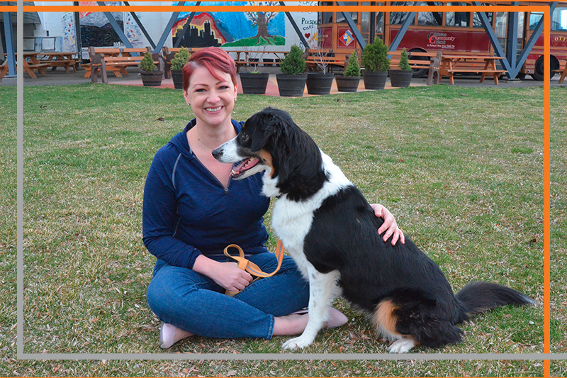 Leslie Stewart in jeans and a blue sweater, with short spiked red hair hugs her dog Star, a trained therapy dog who works with Stewart in providing animal-assisted interventions at the ISU Counseling Clinic