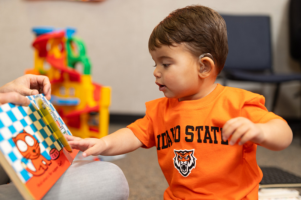 Ethan Estevez, a four-year-old who uses hearing aids to combat hearing loss, plays with a toy in the speech language pathology clinic at ISU.