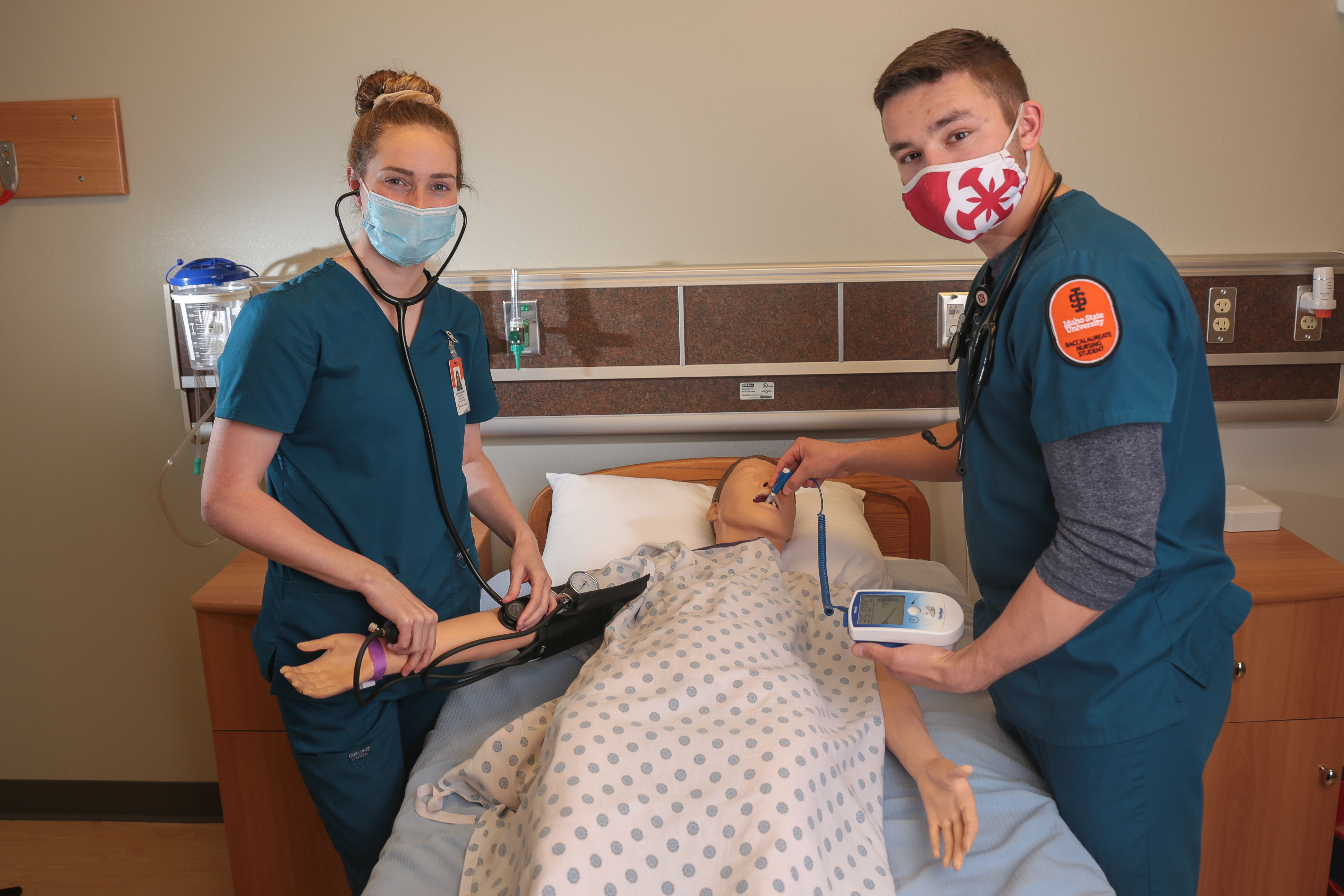 Nursing students work with a simulation manikin to test blood pressure