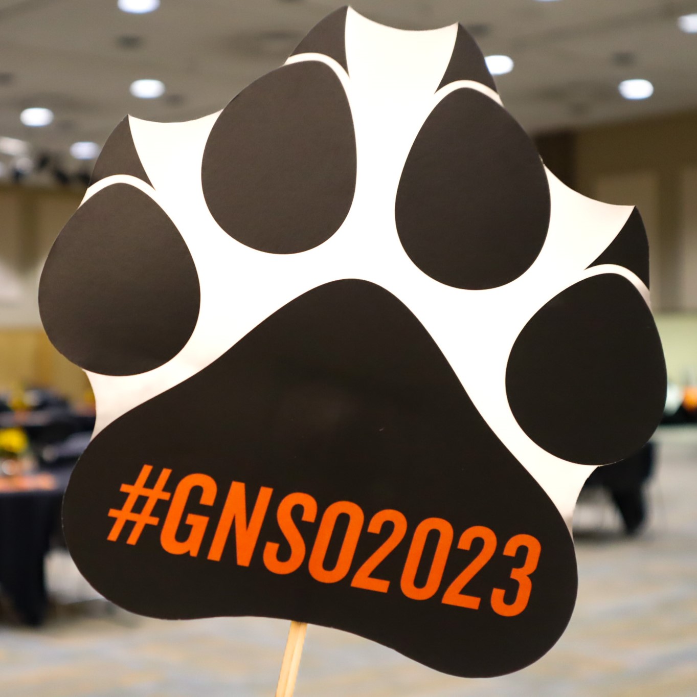 Close up of a photobooth prop shaped like a paw print that says #gnso2023