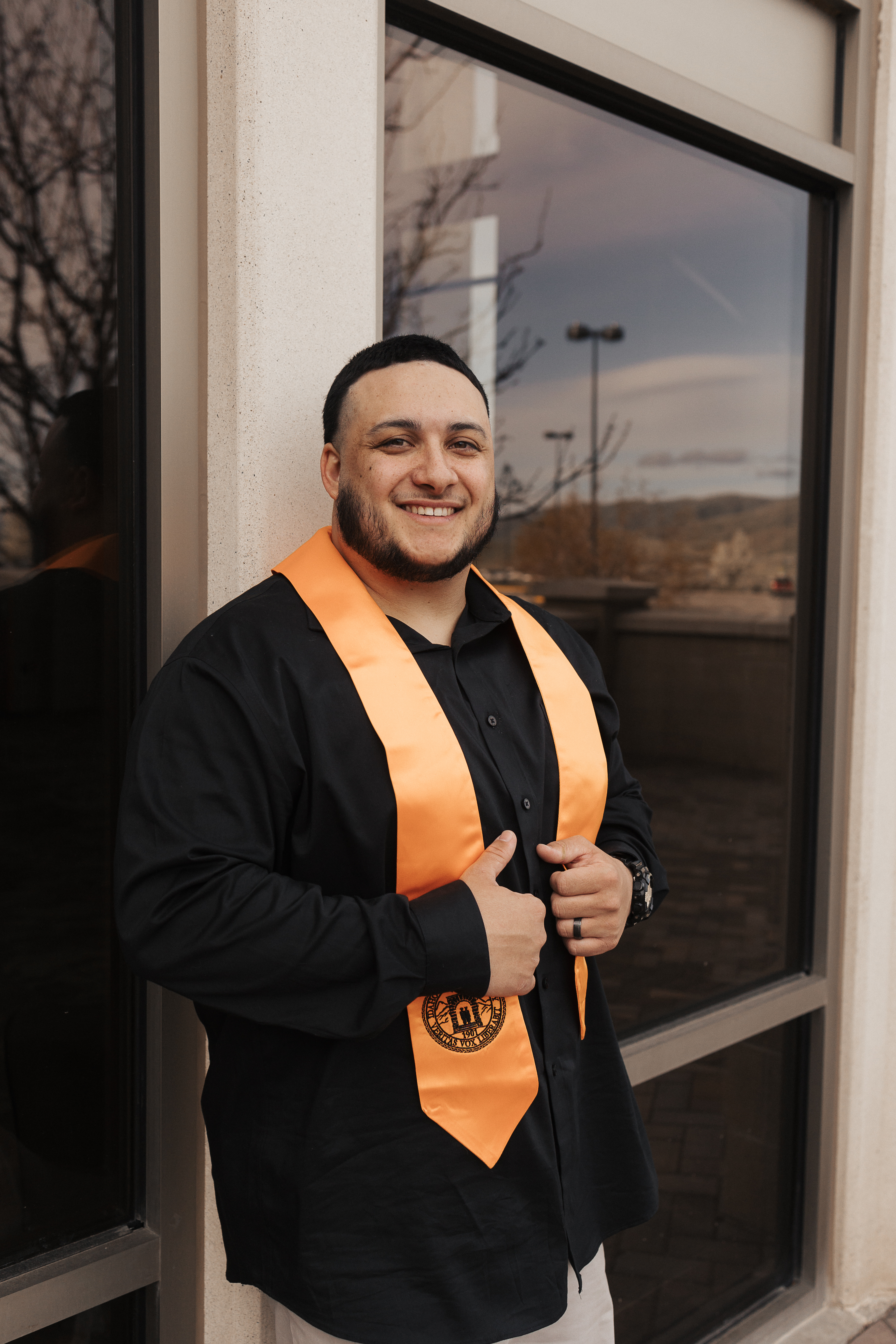 Tyler Hill wearing an ISU sash leaning against a building