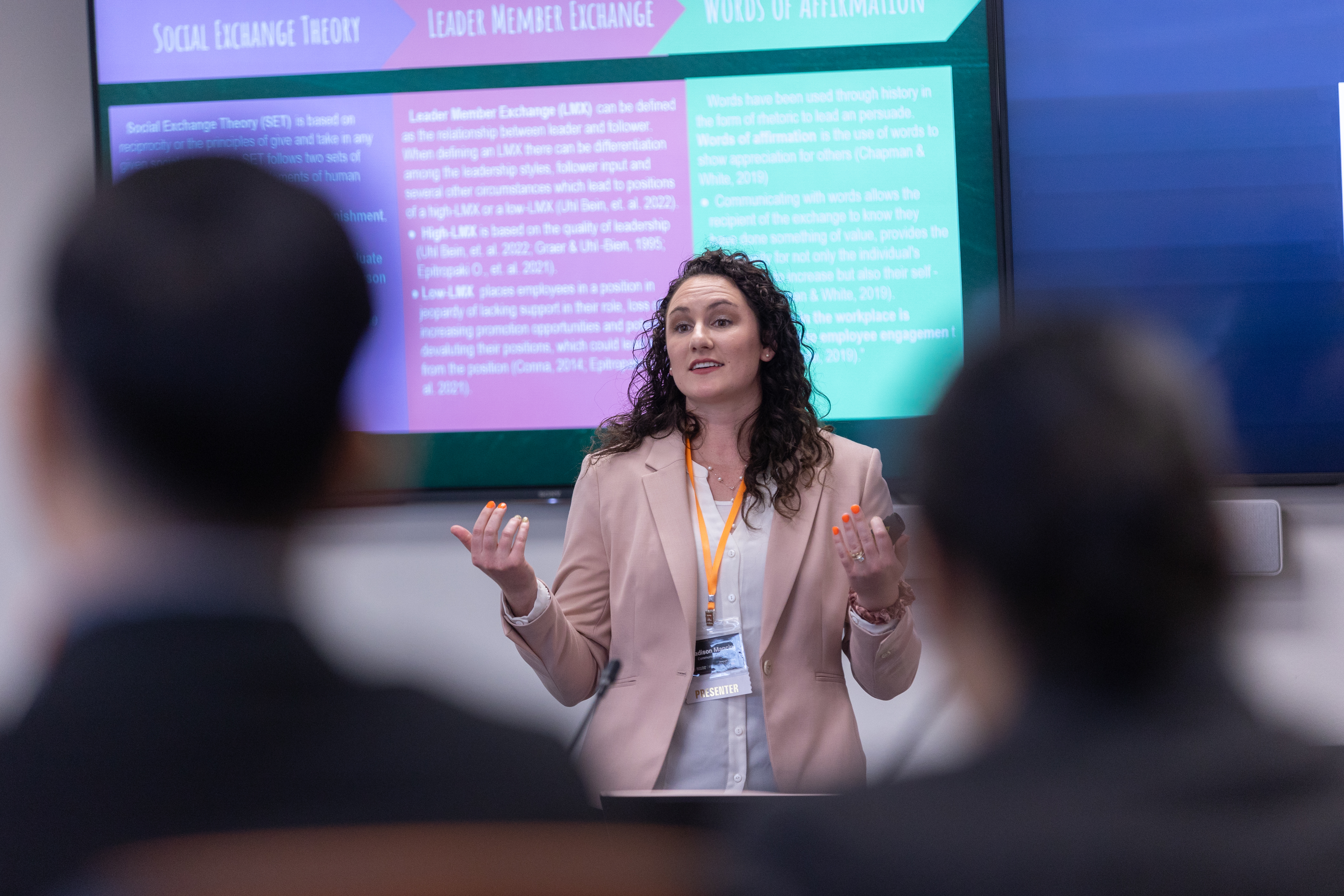 A woman presenting a slide on a tv to an audience