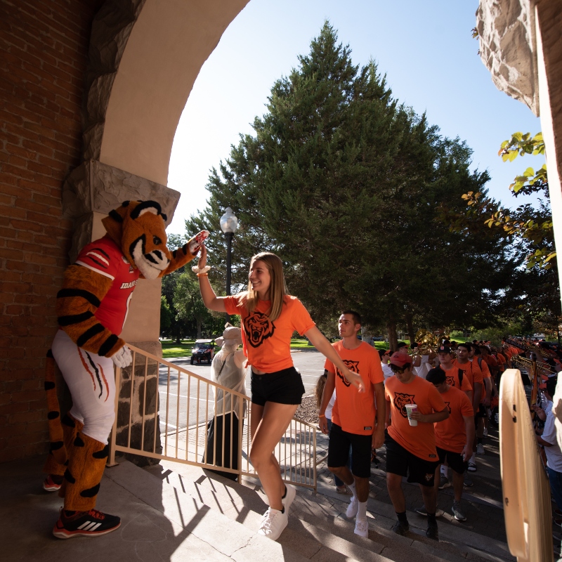 Benny giving new students high-fives as they march through the arch