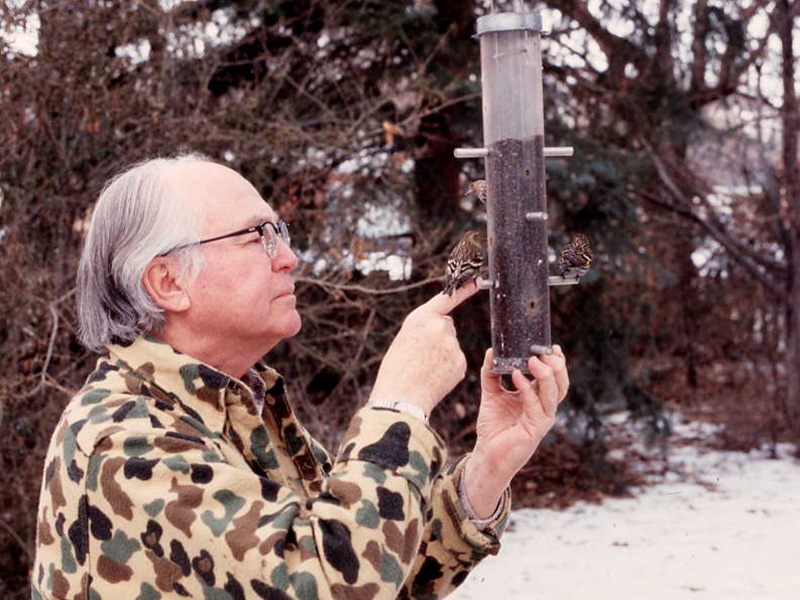 Edson Fichter holding a bird on his finger at a bird feeder