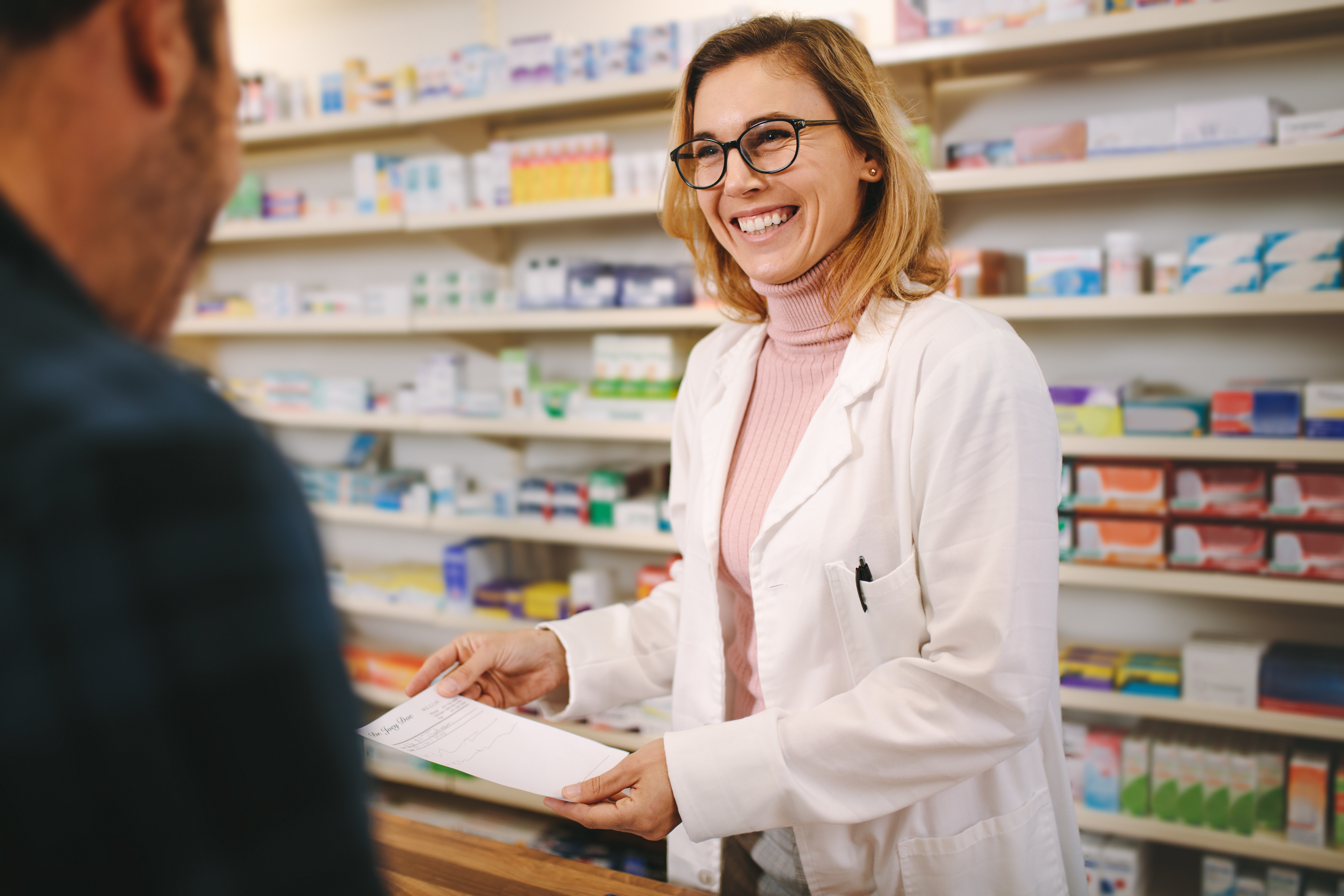 Pharmacist smiling at patient who is receiving a prescription