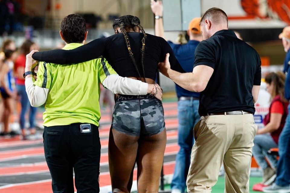 athlete walking being assisted by trainers