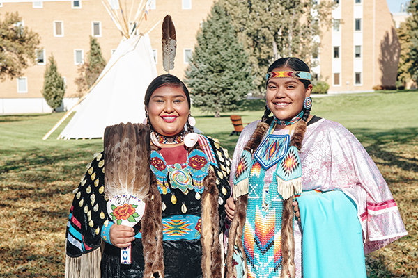 Two Indigenous persons dressed in regalia on the ISU Quad