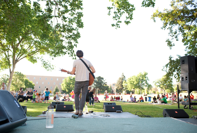 Photo of a member of a band playing a concert on the quad facing out to the audience.