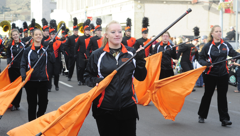 Photo of band members with flags marching in the Homecoming Parade.