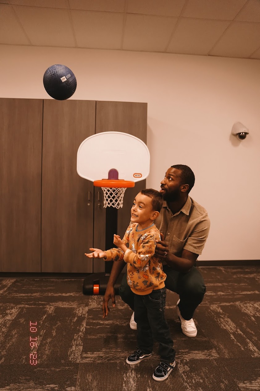Michael Kidd-Gilchrist watches a young boy who uses an augmentative and alternative communication device play basketball at the ISU Meridian Speech Language clinic