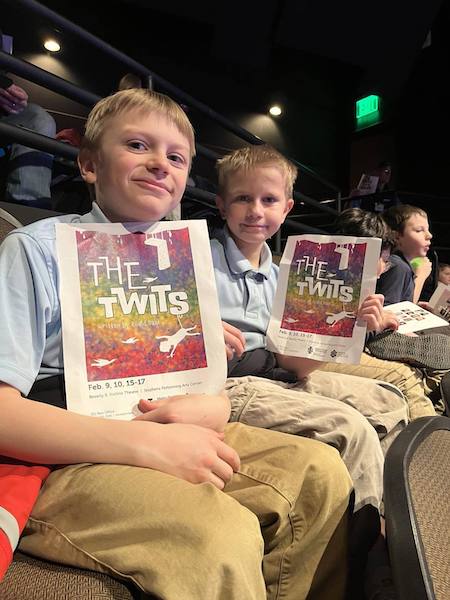 Two boys hold a theater pamphlet