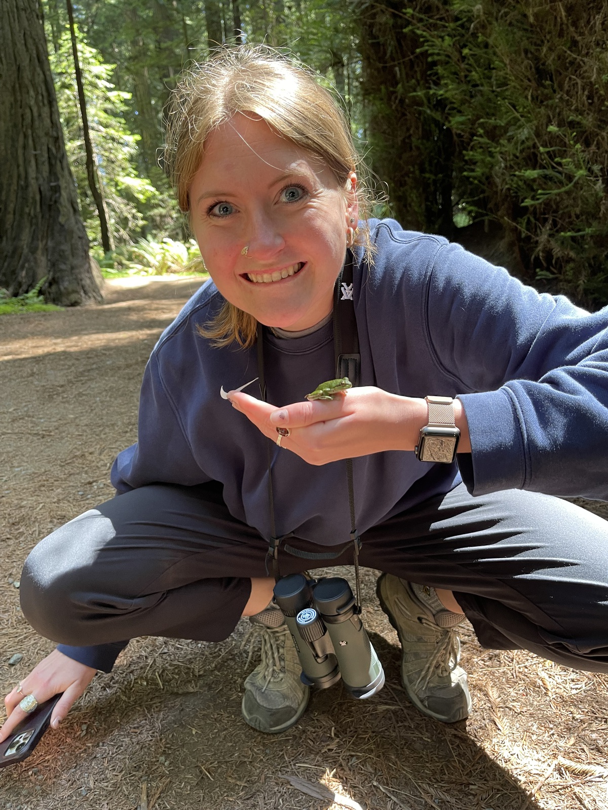 Hannah Clawson holding a tiny frog in a stream