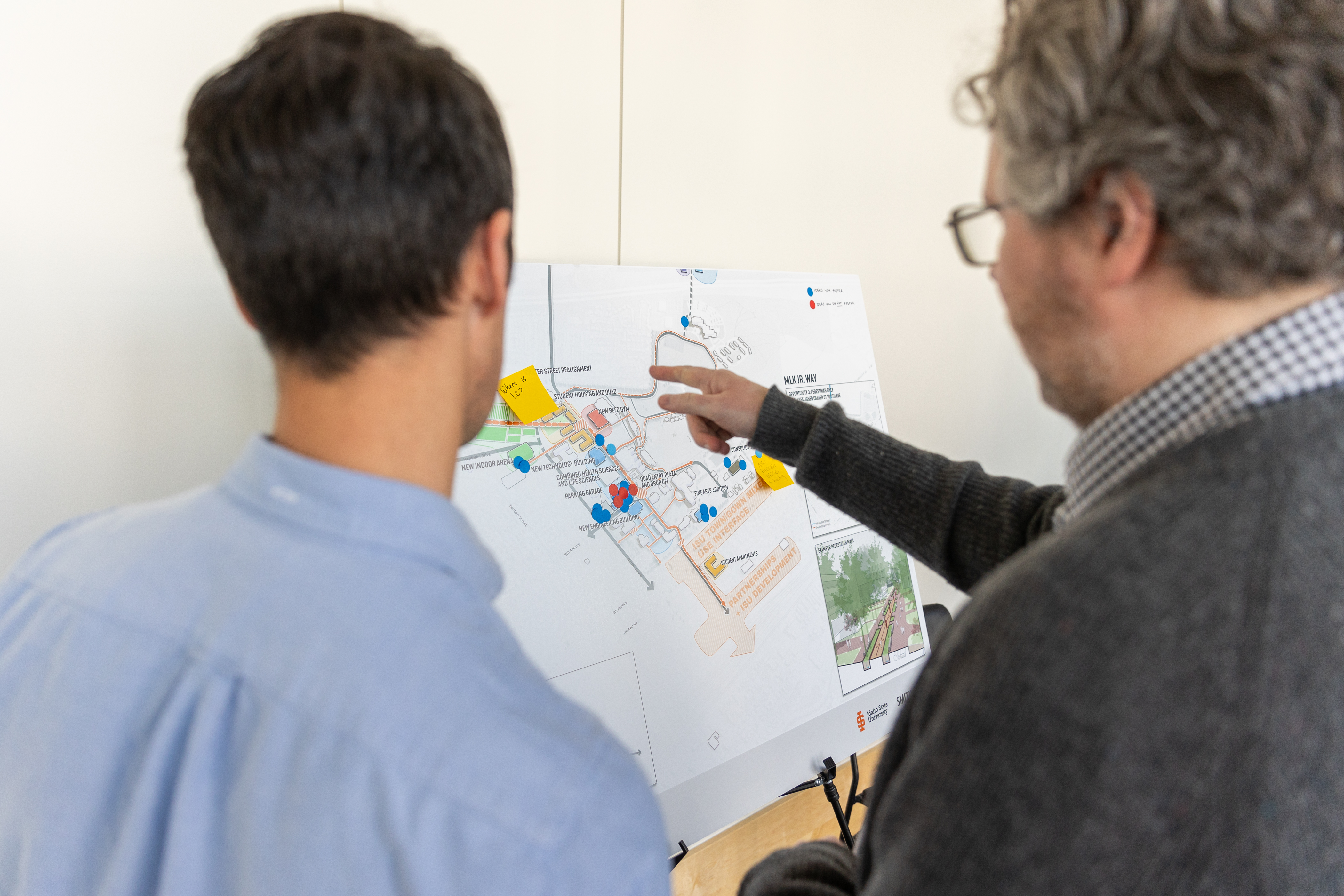 Two men look over a proposed design for the Pocatello campus during a campus master plan feedback session