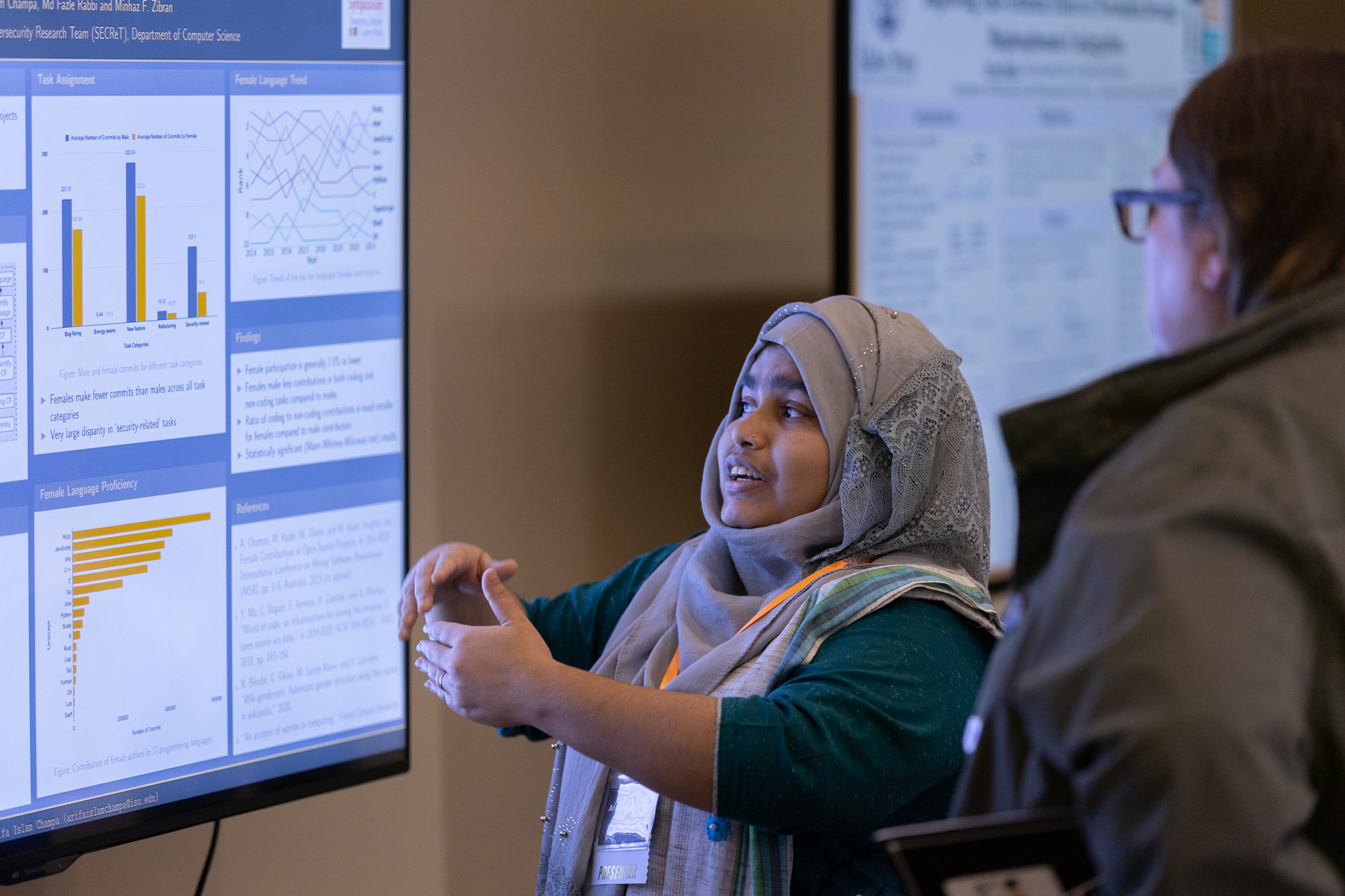 A participant at the 2023 Graduate Research Symposium presents their research to an engaged listener