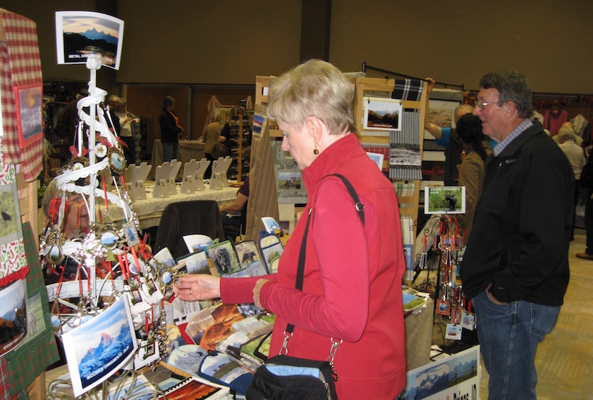 Photo of a woman at a previous Women's Holiday Fair looking at items on a table. 