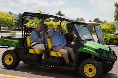 Picture of small four-wheeled John Deere vehicle with members of the Wheatley family on board, during a tour of campus.