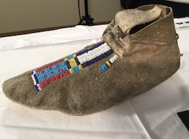 A photo of a beaded moccasin that is on display. 
