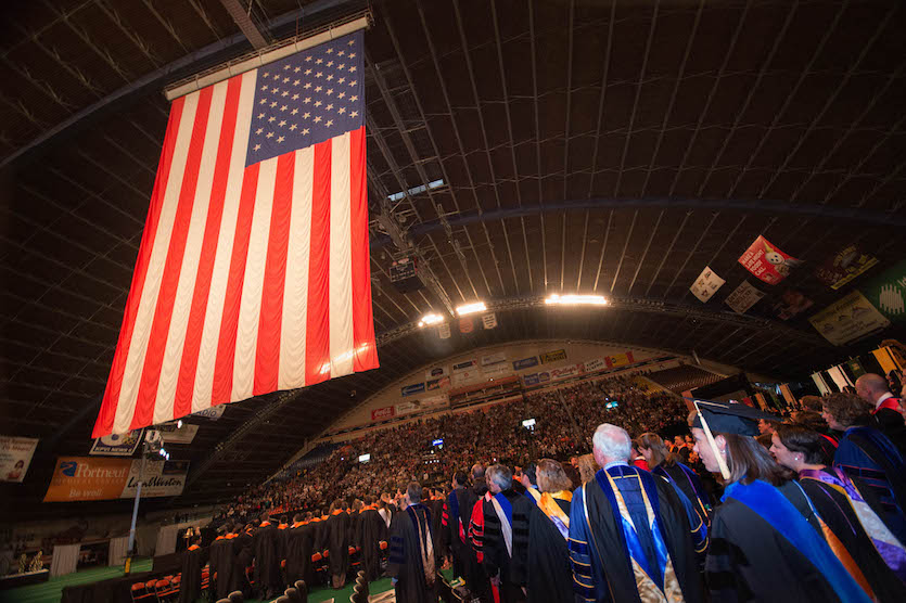 A picture of Holt Arena and flag and guests at commencement