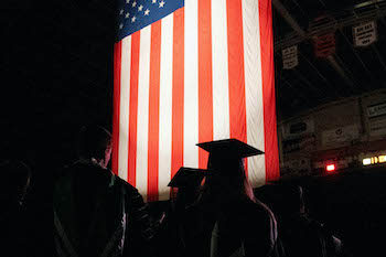 U.S. Flag lit up with students in foreground.