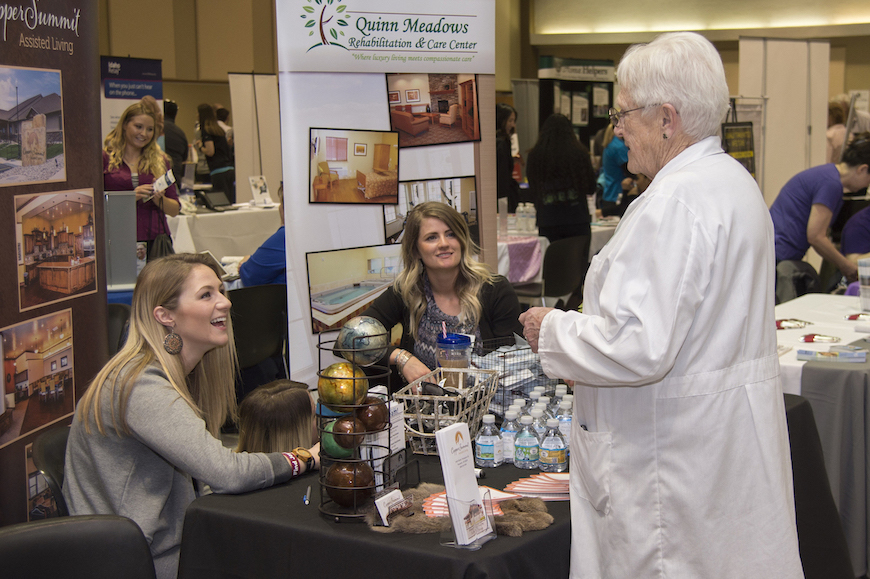 Photo from 2017 health fair, woman talking to two women at a booth. 