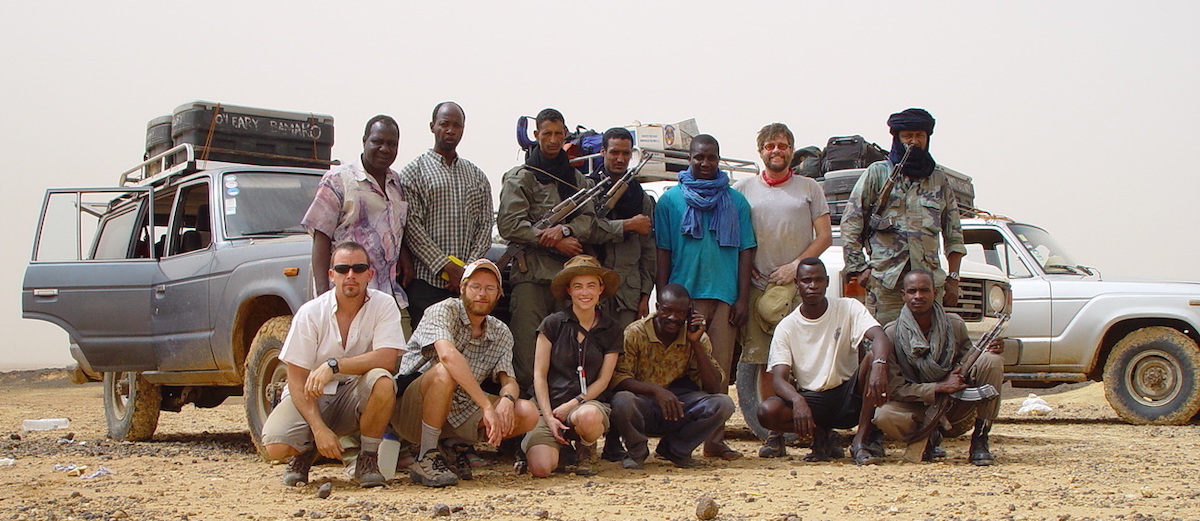Mali researchers and guards posing in front of vehicles during 2003 trip.