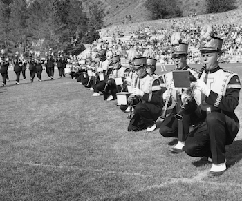 marching band members kneeling on the field at the Spud Bowl. 